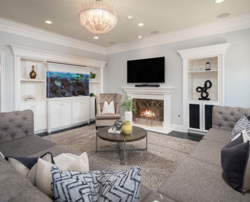 Bright living room with fireplace, built-in cabinetry, aquarium feature, and neutral seating arranged around a central coffee table Bright living room with fireplace, built-in cabinetry, aquarium feature, and neutral seating arranged around a central coffee table