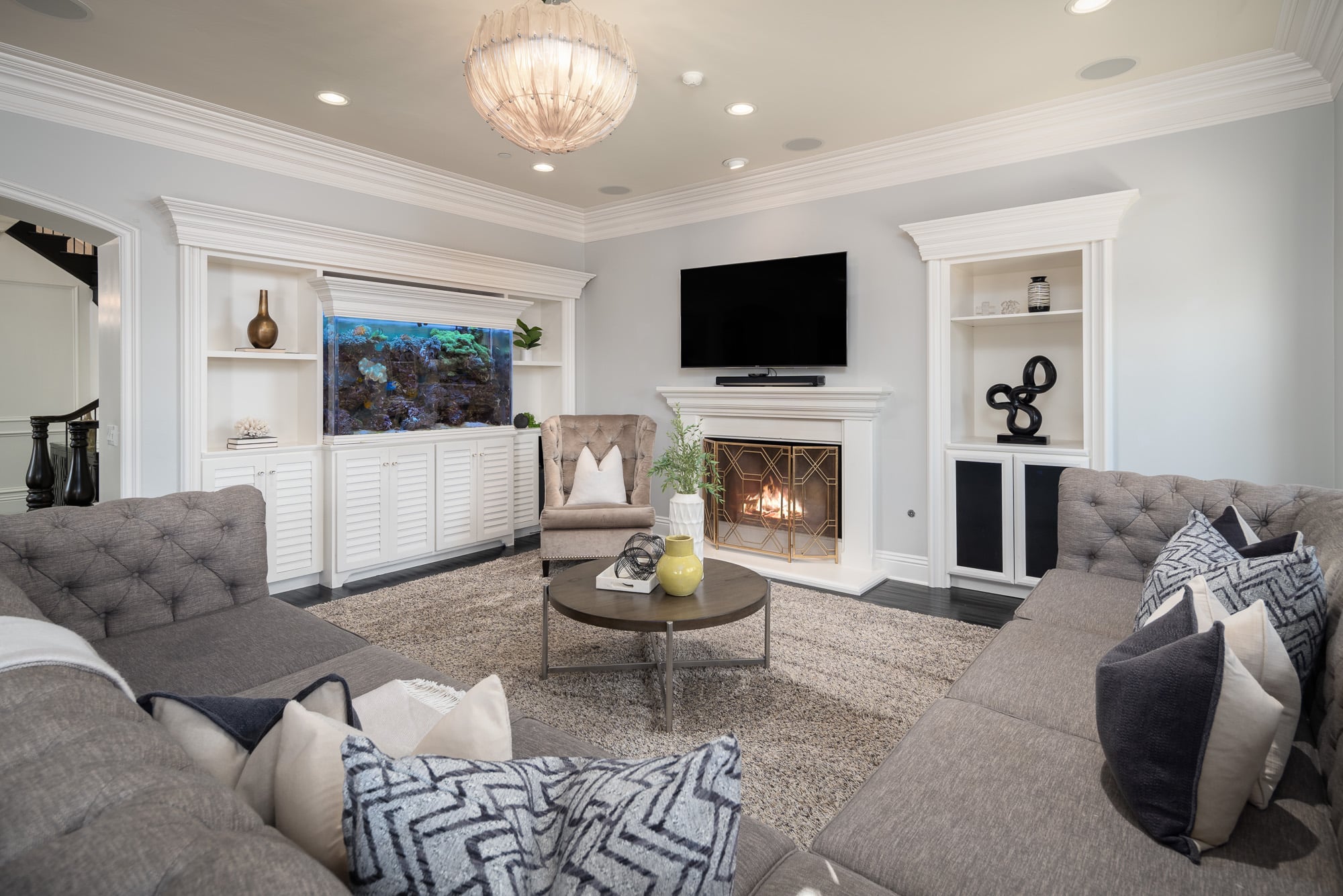 Bright living room with fireplace, built-in cabinetry, aquarium feature, and neutral seating arranged around a central coffee table Bright living room with fireplace, built-in cabinetry, aquarium feature, and neutral seating arranged around a central coffee table