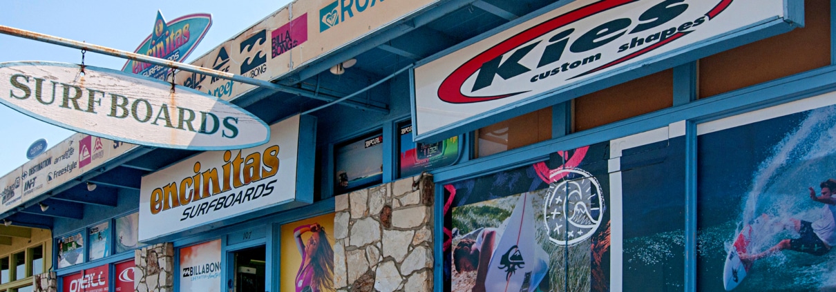 Local surf shops along Coast Highway in Encinitas with custom surfboards, brand signage, and a laid-back coastal streetscape