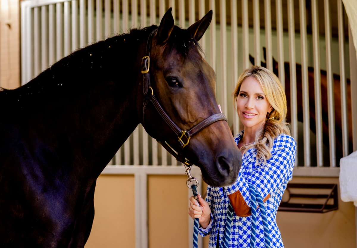 Priscilla Wood Balikian standing with a horse in a Rancho Santa Fe stable, reflecting the area’s equestrian heritage and tradition