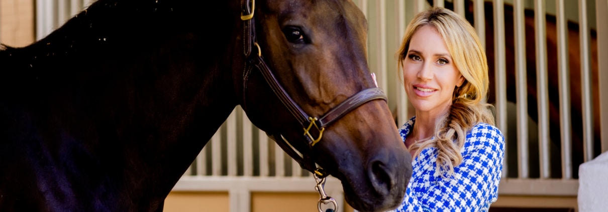 Priscilla Wood Balikian standing with a horse in a Rancho Santa Fe stable, reflecting the area’s equestrian heritage and tradition