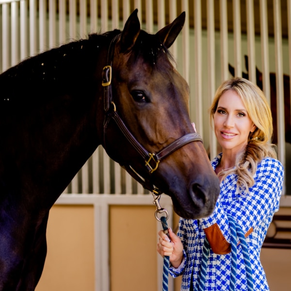 Priscilla Wood Balikian standing with a horse in a Rancho Santa Fe stable, reflecting the area’s equestrian heritage and tradition