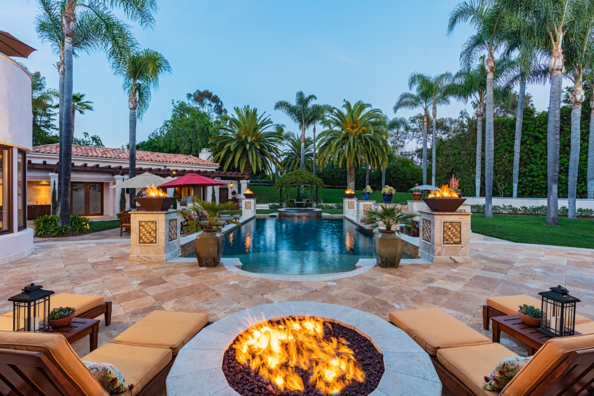 Evening outdoor living space in Rancho Santa Fe with fire pit, pool, palm trees, and seating designed for relaxed gatherings