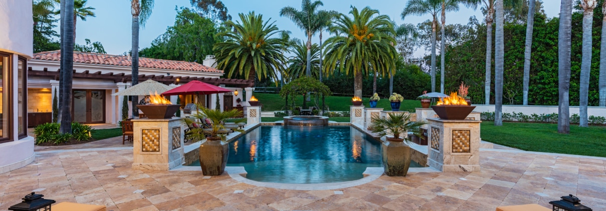 Evening outdoor living space in Rancho Santa Fe with fire pit, pool, palm trees, and seating designed for relaxed gatherings