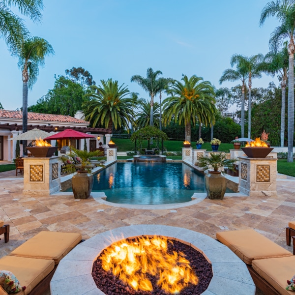 Evening outdoor living space in Rancho Santa Fe with fire pit, pool, palm trees, and seating designed for relaxed gatherings