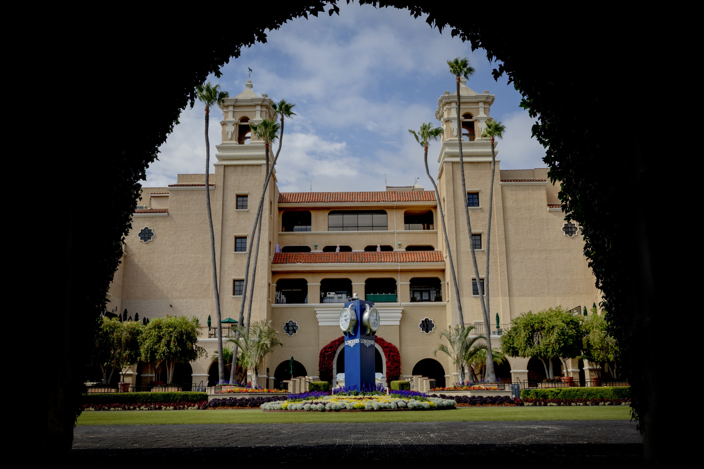 Framing the entrance to a timeless race day tradition. Del Mar Racetrack entrance framed by archway with clock tower and palm trees