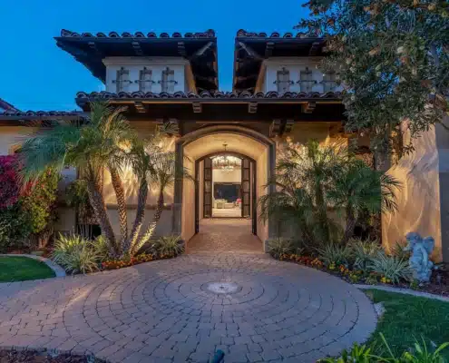 Arrival at a Bridges Rancho Santa Fe Estate Front entry of a luxury estate at The Bridges Rancho Santa Fe with arched doorway and evening lighting