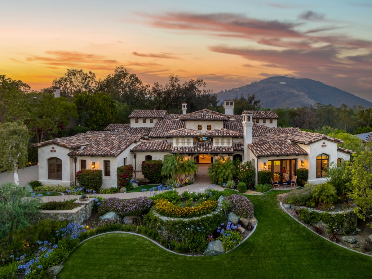 Single-level luxury estate at The Bridges Rancho Santa Fe with landscaped gardens and sunset sky