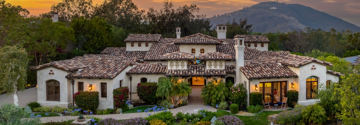 Single-level luxury estate at The Bridges Rancho Santa Fe with landscaped gardens and sunset sky