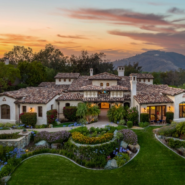 Single-level luxury estate at The Bridges Rancho Santa Fe with landscaped gardens and sunset sky
