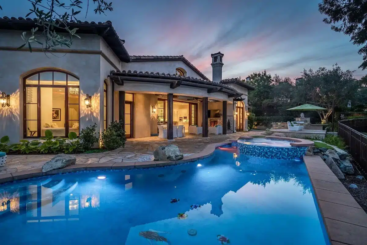 Evening Living at The Bridges Rancho Santa Fe Rear exterior of a single-level estate with pool and patio at The Bridges Rancho Santa Fe during twilight