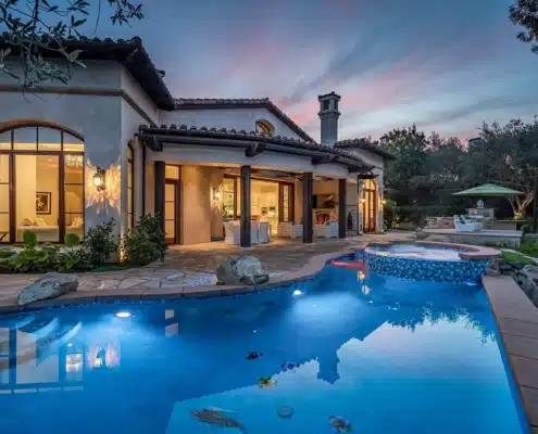 Evening Living at The Bridges Rancho Santa Fe Rear exterior of a single-level estate with pool and patio at The Bridges Rancho Santa Fe during twilight