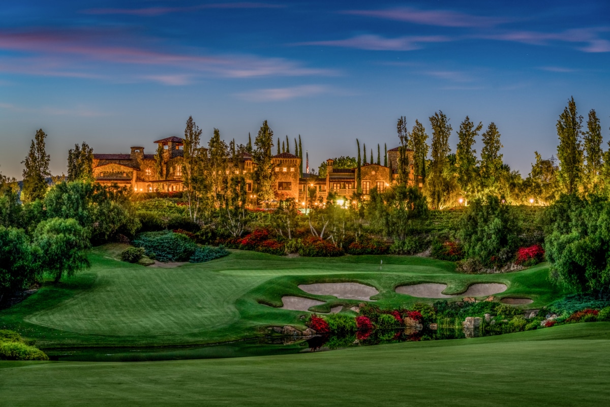 Twilight view of The Bridges golf course and estate homes in Rancho Santa Fe with rolling fairways and illuminated residences.