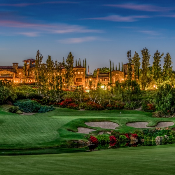 Twilight view of The Bridges golf course and estate homes in Rancho Santa Fe with rolling fairways and illuminated residences.