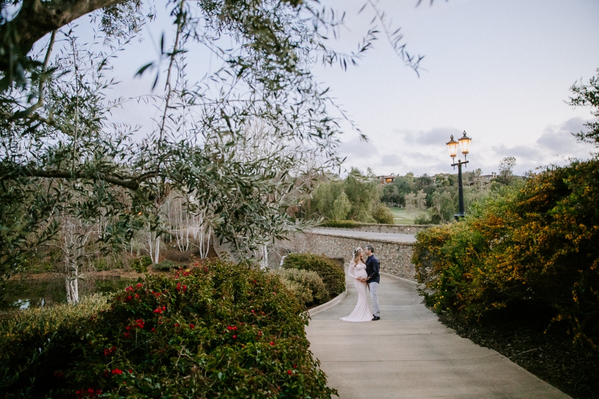 Priscilla and her husband capturing a moment within The Bridges’ landscape Couple walking together along a garden path near a stone bridge at The Bridges Rancho Santa Fe